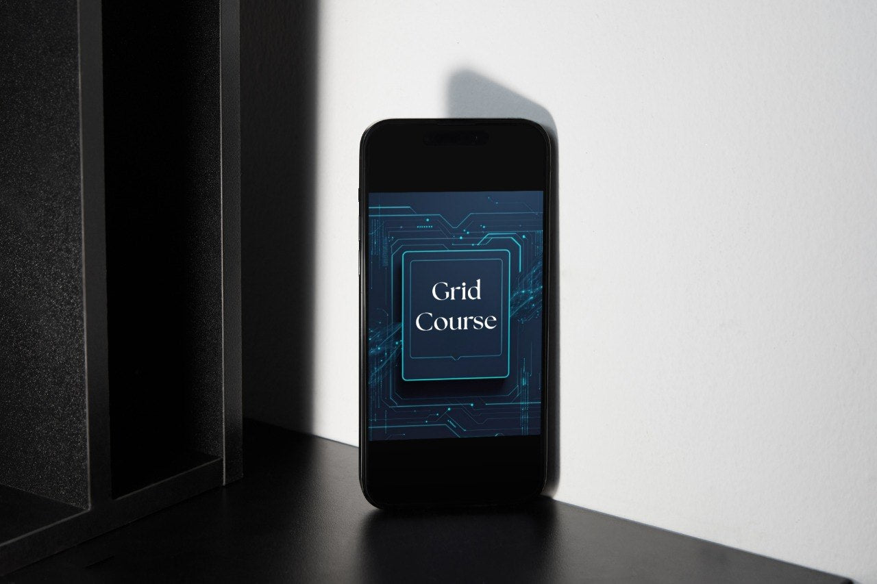 A black smartphone standing upright on a dark surface against a white wall, displaying a blue tech-style screen with the words 'Grid Course'.