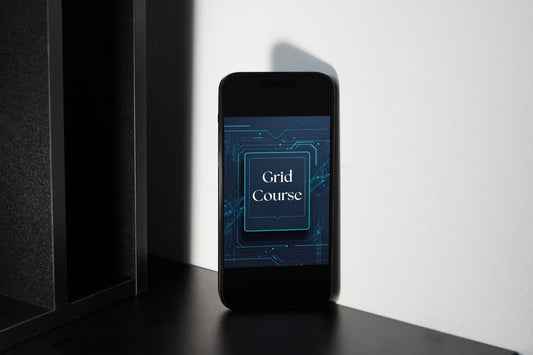 A black smartphone standing upright on a dark surface against a white wall, displaying a blue tech-style screen with the words 'Grid Course'.
