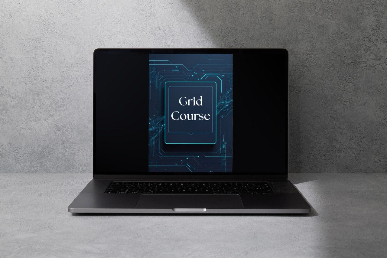 A dark gray laptop is open and centered on a light gray surface against a textured gray wall. The screen displays a digital graphic with the words 'Grid Course' in white over a blue circuit-board design.